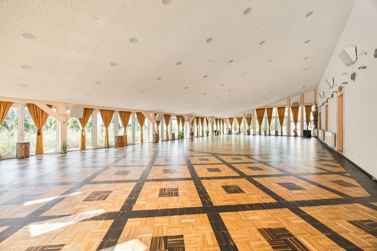 Der große Saal mit Parkettboden und goldenen Vorhängen