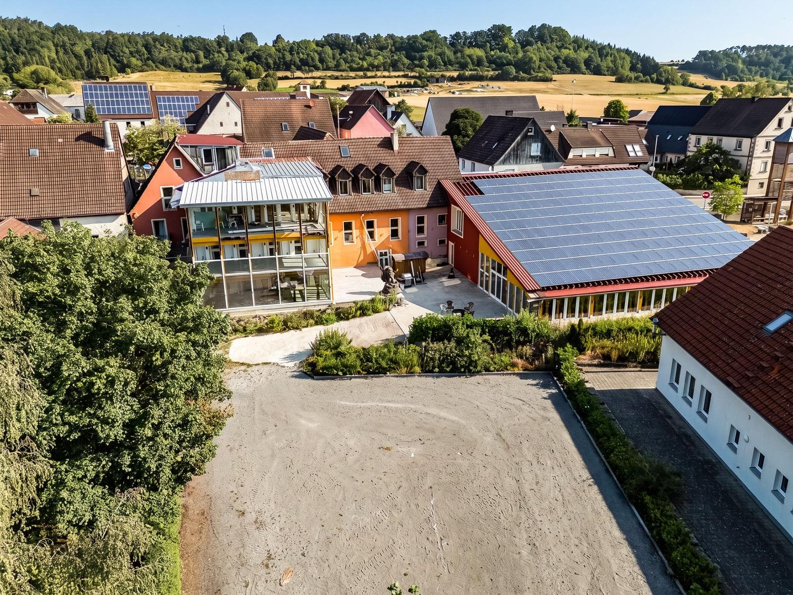 Luftaufnahme über das ganze Gelände von Punkt XII im Steigerwald – gläserner Wintergarten, Innenhof und die große Solarhalle