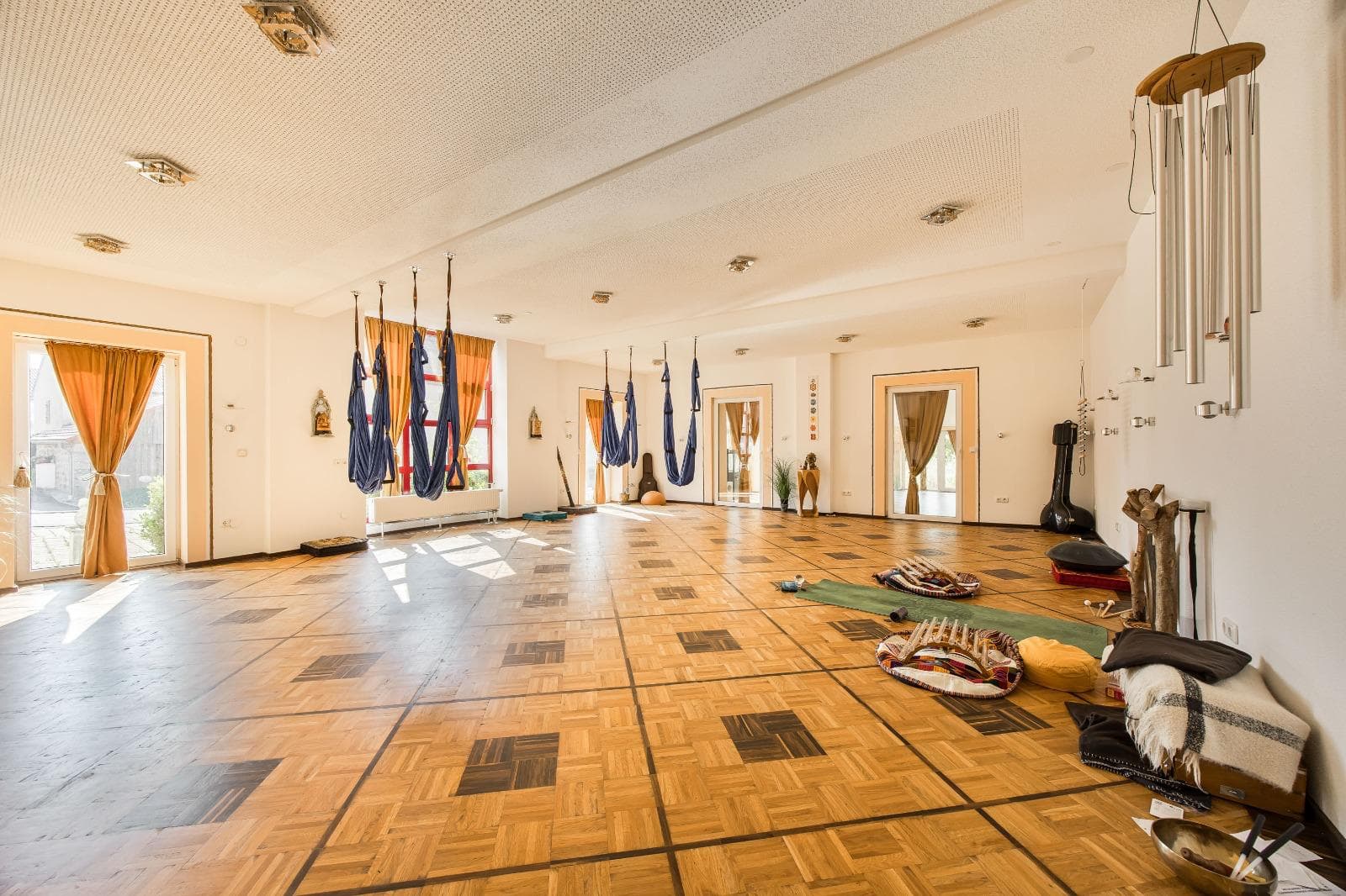 Große Yoga-Halle mit Aerial-Yoga-Tüchern und Parkettboden