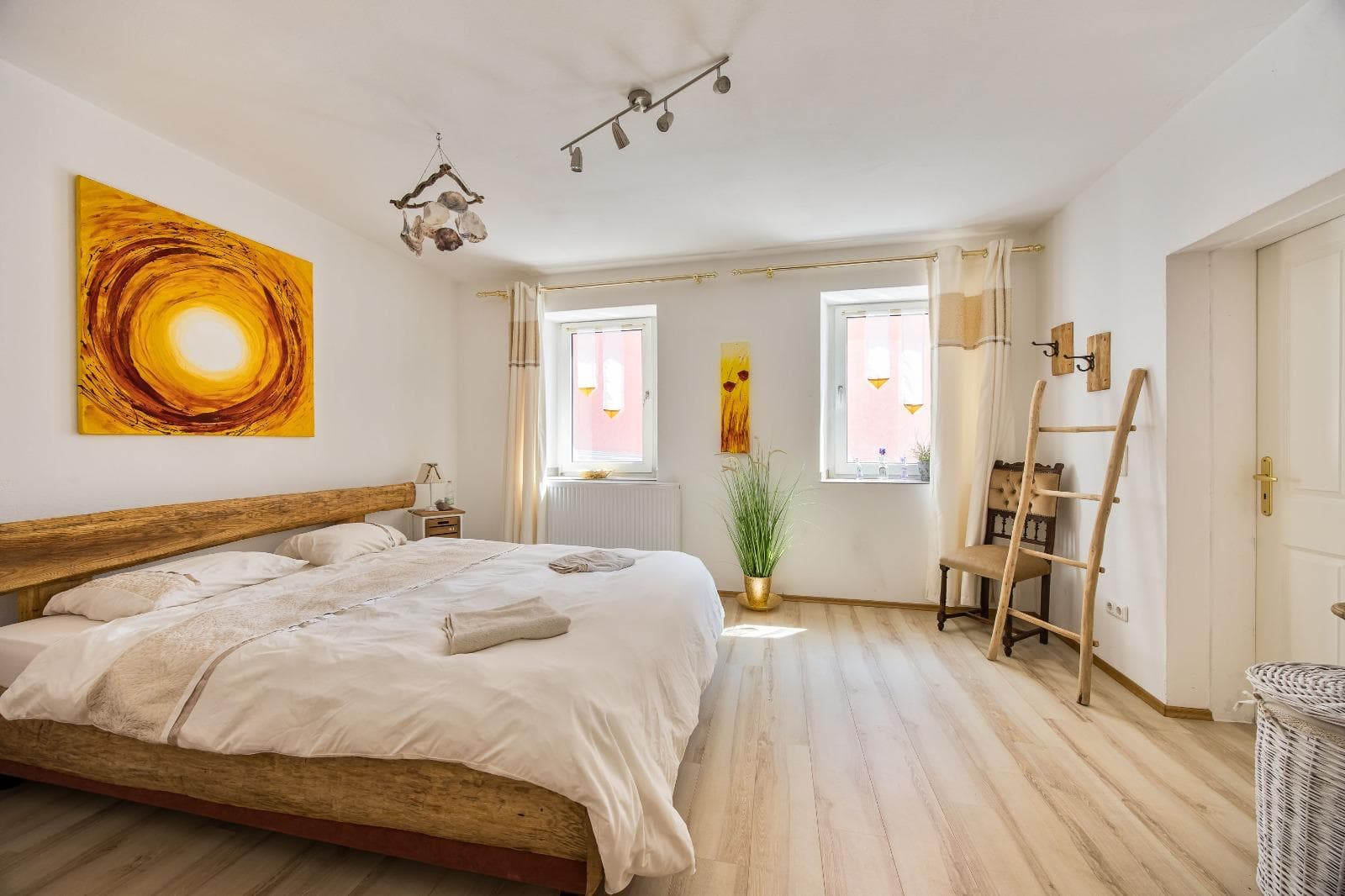 Bright double room with sun painting and wooden bed