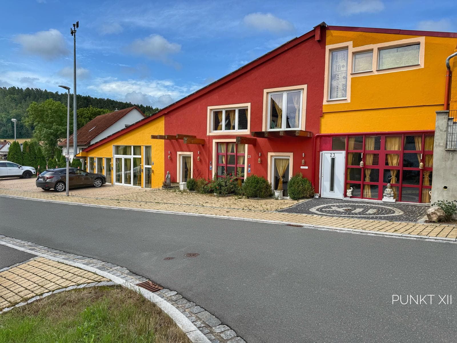 The red and yellow houses of Punkt XII with parking on the village street in Oberrimbach