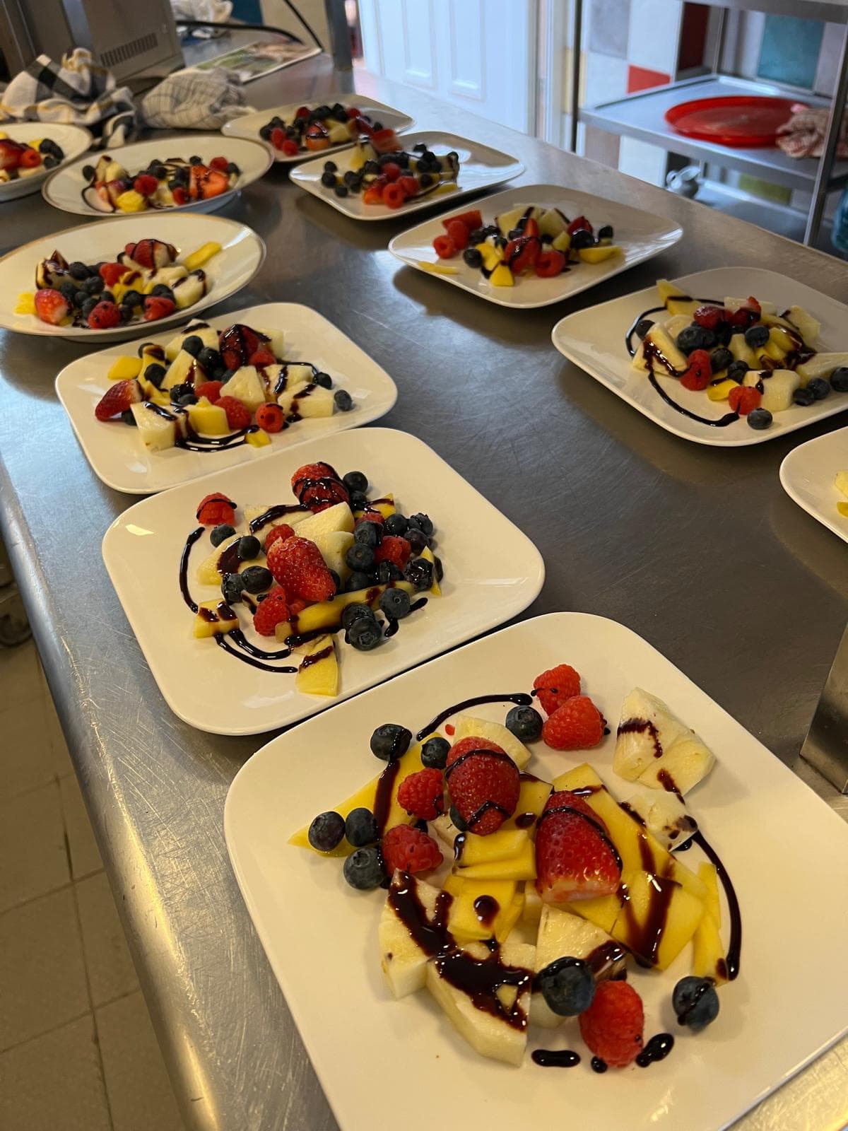 Frisch angerichtete Obstteller mit Erdbeeren, Heidelbeeren, Mango und Melone – aus der Gemeinschaftsküche von Punkt XII